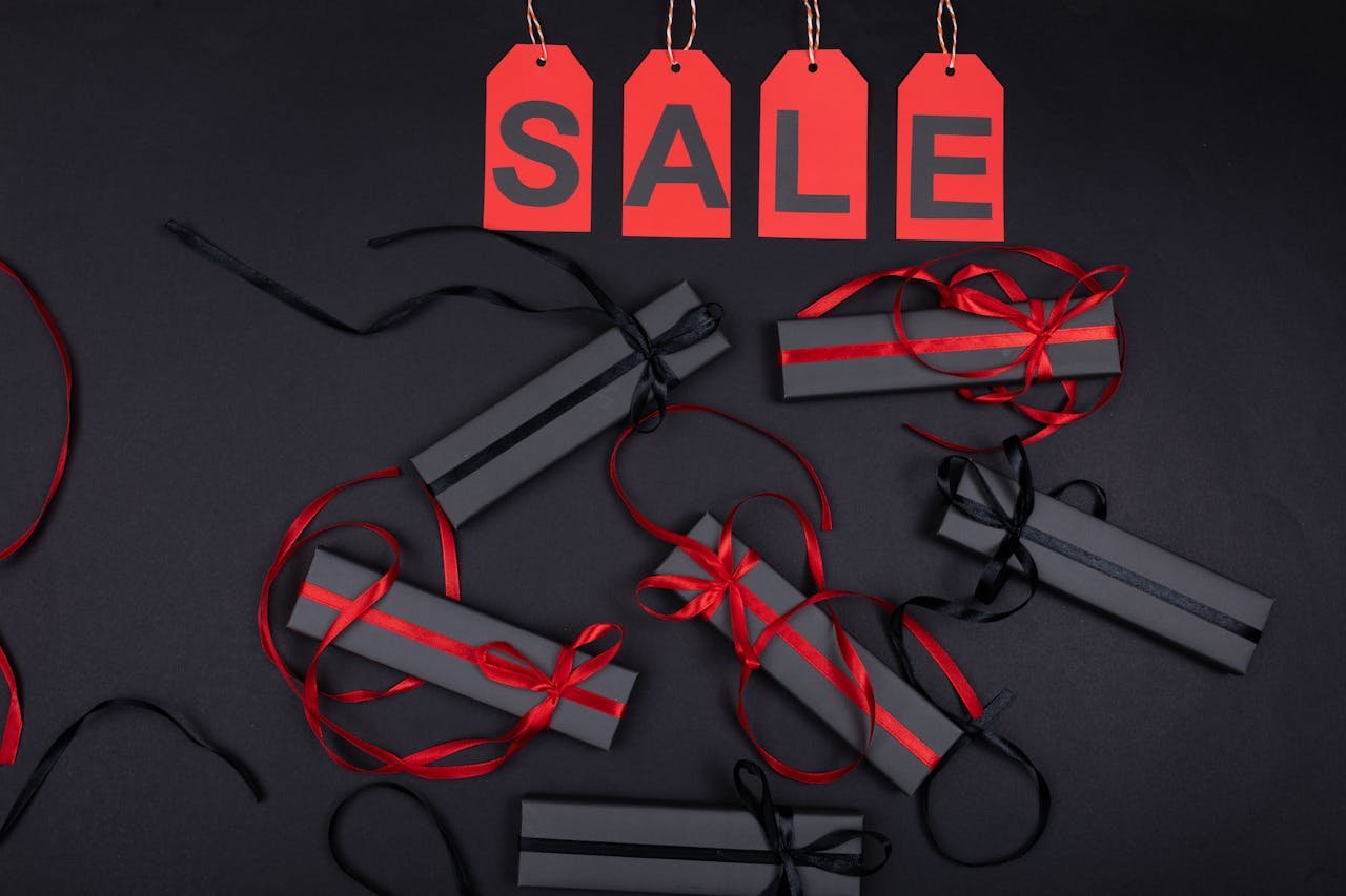 Elegant black gift boxes with red ribbons on sale promotion background.